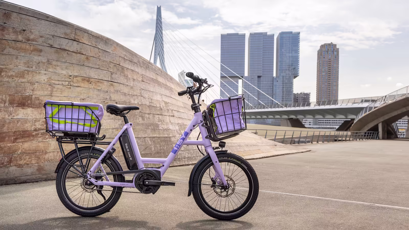 Vollausgestattetes i:SY E5 ZR F Pastel Purple mit Doppel-Taschen-Setup vor imposanter Brücken-Kulisse