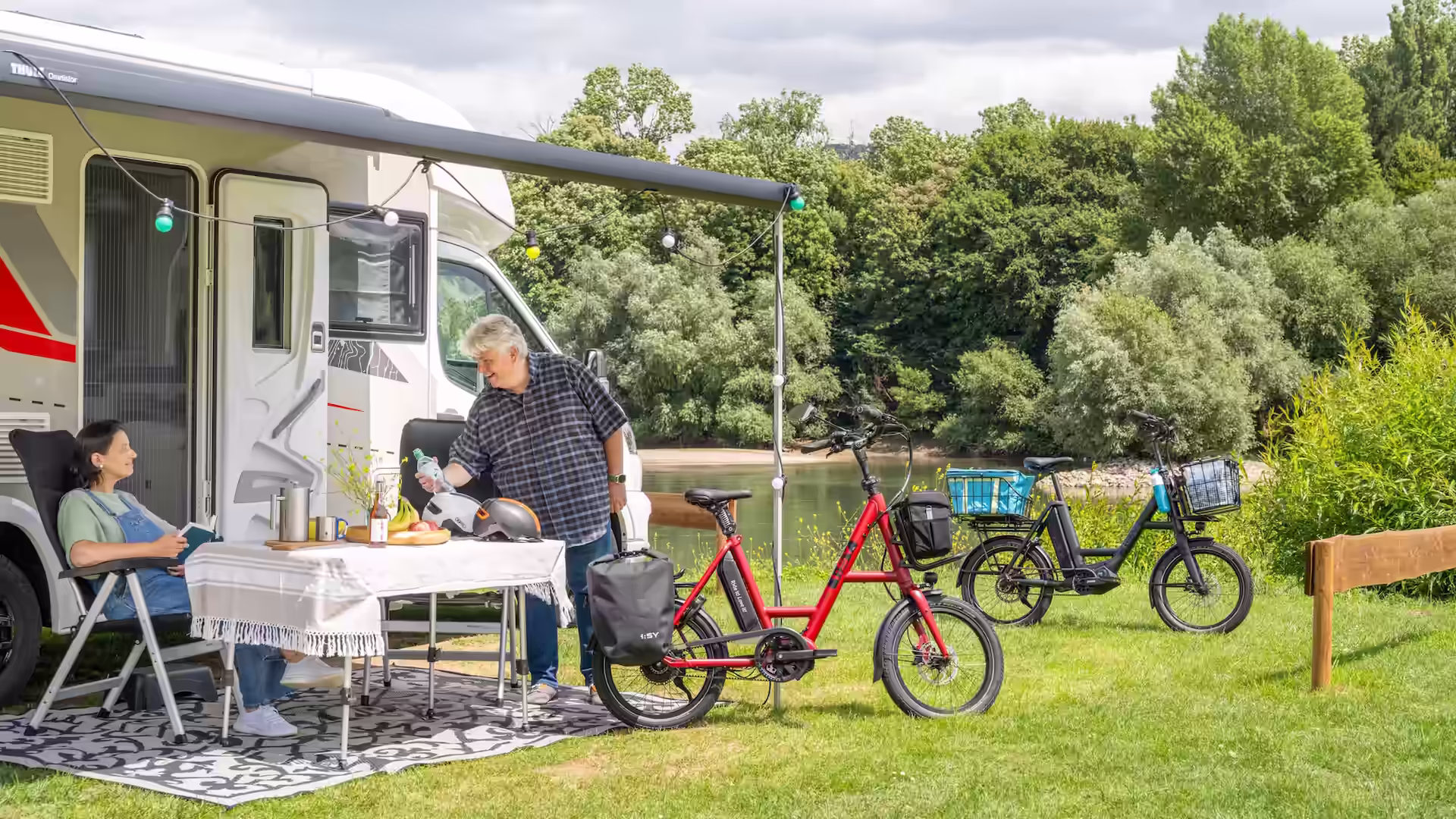 John und Tine genießen ihren sonnigen Stellplatz bei der i:SY Caravan Tour am Rhein