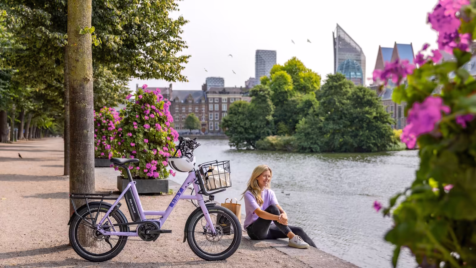 Entspannte Pause am Grachtenufer mit dem i:SY E5 und Blick auf moderne Skyline-Architektur